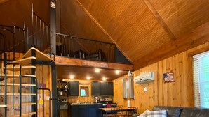 Un vaste espace de vie comprenant un escalier en bois, une table à manger, un canapé et une cuisine à l’arrière-plan.