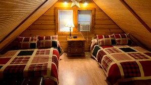 Une chambre mansardée chaleureuse, avec deux lits, un bureau et un luminaire en forme d’étoile.