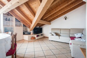 Un salon avec un téléviseur, un canapé et des poutres en bois.