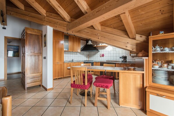 A kitchen with wooden beams, a tiled floor, and wooden cabinets.