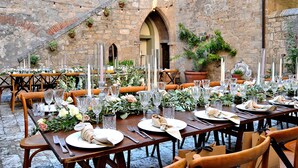 An outdoor dining area with stone walls, wooden tables, and chairs. - Panoramic castle with large pool on the walls. Ideal for weddings and events (Poggibonsi)