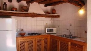 A kitchen with wooden cabinets, a white refrigerator, a microwave, and a sink. - Country holiday home - San jose (sant Josep de sa Talaia)