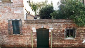 A brick building with a green-tinted water feature in front. - Ca' Venexiana, quiet 2 bedroom with private canalside courtyard - no added fees! (Venezia)