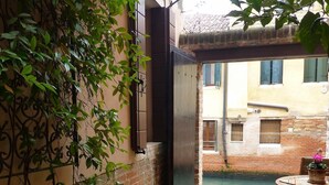 A courtyard with a brick floor, a table with chairs, and potted plants. - Ca' Venexiana, quiet 2 bedroom with private canalside courtyard - no added fees! (Venezia)