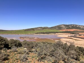 Un paisaje con un lago, colinas y aerogeneradores.