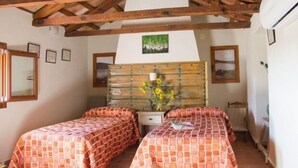 Ein Zimmer mit zwei Betten, Holzbalken an der Decke, einem Schminktisch und einem an der Wand befestigten Bild.