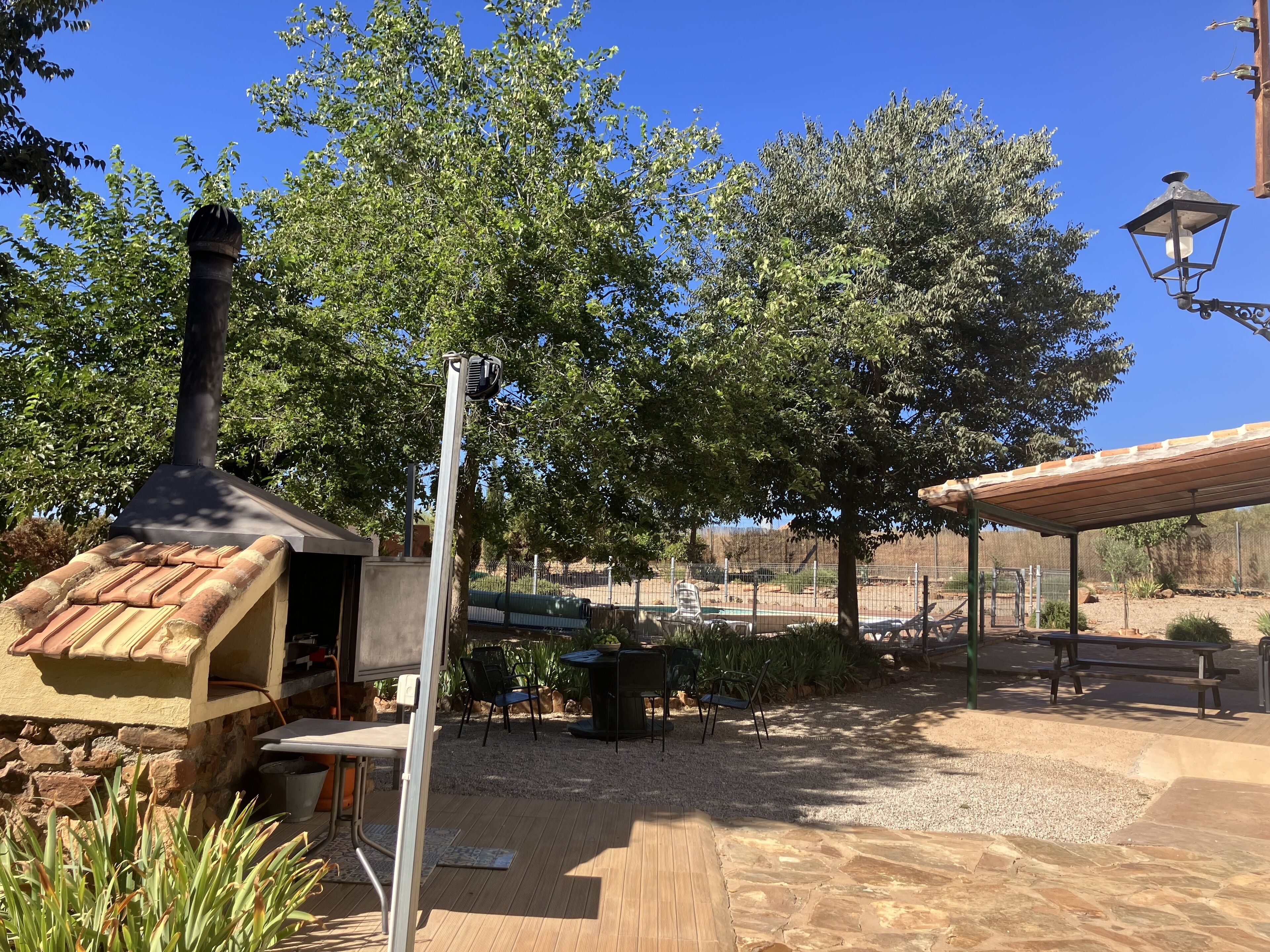 Un espace extérieur aménagé en terrasse, doté d’une cheminée, de sièges et d’une pergola.