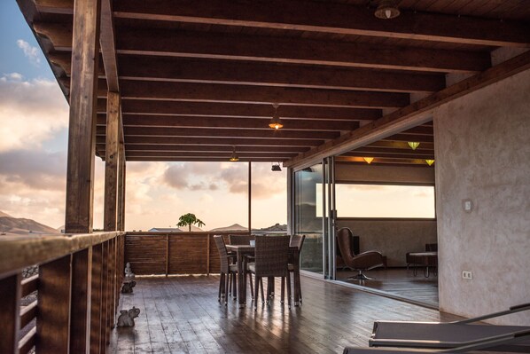 A wooden deck with a table and chairs, overlooking a scenic landscape. - Eco-Villa immersed in a natural park of volcanic origin. (Villaverde)