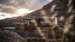 Una casa moderna con piscina, rodeada de un paisaje rocoso y montañas.