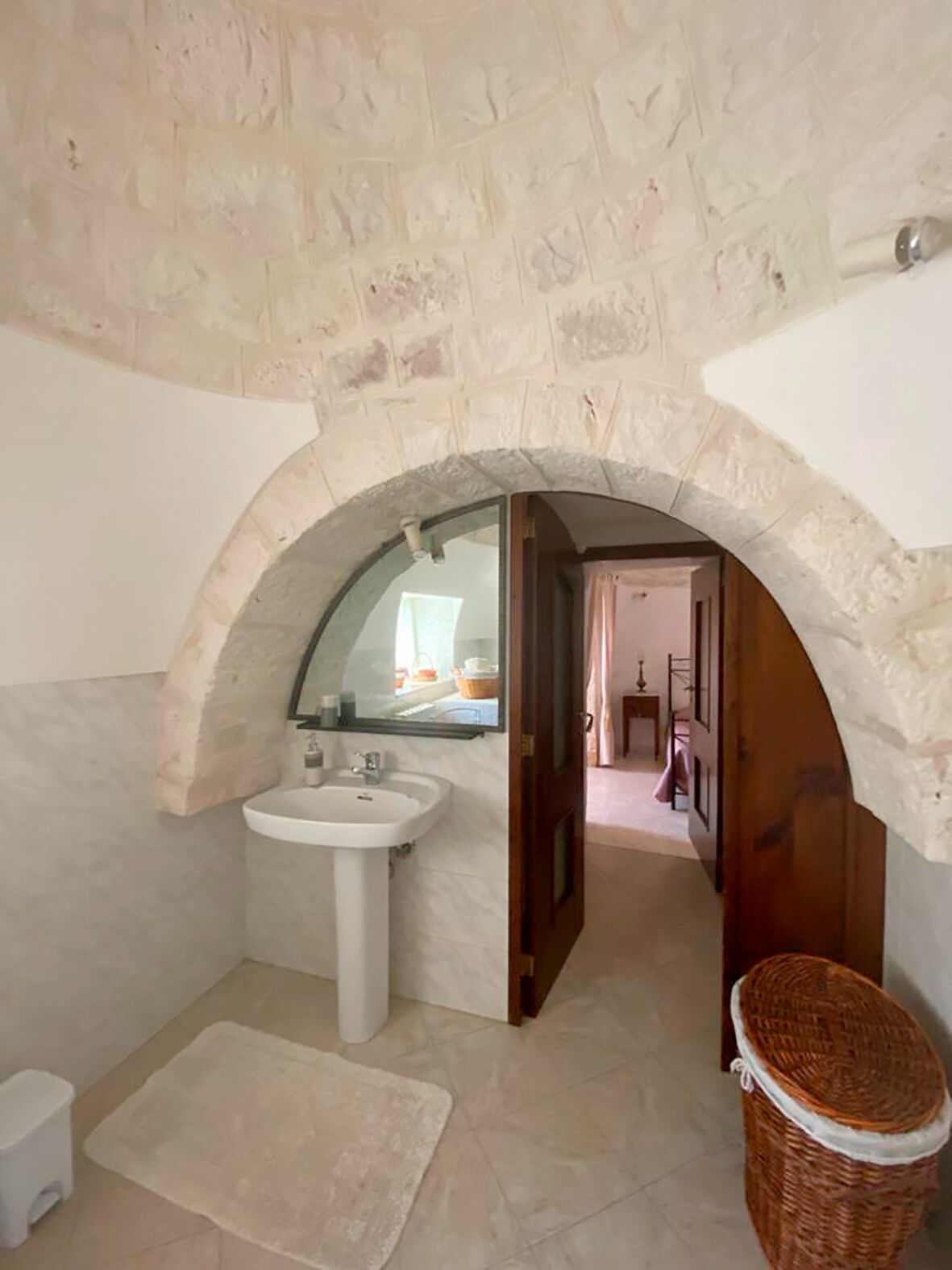 A bathroom with a stone arch, a white sink, and a mirror.
