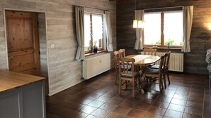 Un comedor con una mesa y sillas de madera, una ventana con cortinas y un radiador debajo de la ventana.