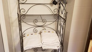 A metal towel rack with two shelves, each holding folded towels.