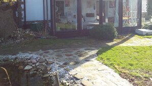 A modern house with large glass windows, a stone pathway, and a small water feature.
