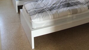 A bedroom with two single beds, a window with curtains, a radiator, and a framed picture on the wall. - House Roy, 3 room apartment in the redeveloped house  (Zülpich)