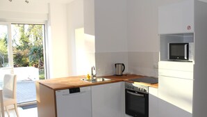 A modern kitchen with white cabinetry, a wooden countertop, a built-in microwave, and a dishwasher. - House Roy, 3 room apartment in the redeveloped house  (Zülpich)
