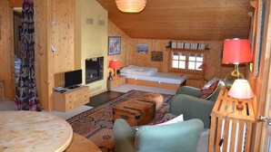 Una cabaña acogedora de madera con televisor, sofá y cama.
