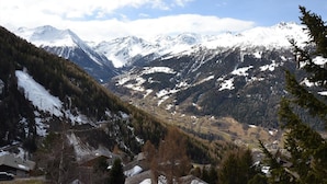 Un paisaje montañoso con picos nevados, un valle con edificios dispersos y un cielo despejado.
