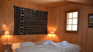 Una habitación con paneles de madera, una cama, dos lámparas de noche, un ventanal y un tapiz en la pared.