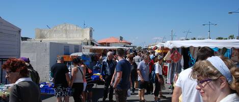 A crowded outdoor market with various stalls and people browsing.
