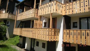A multi-story building with balconies featuring wooden railings and heart-shaped cutouts. - Ground level for 4 pers, superb setting 164 yards from the ski runs et the shops (Les Deux-Alpes)