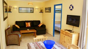 Una sala de estar con sofá, sillones, mesa de centro, televisor y un mueble de madera.