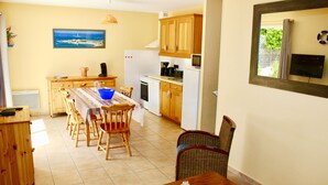 Una cocina con armarios de madera, una mesa de comedor con sillas y un cuadro en la pared.