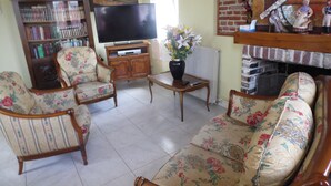 A living room with a sofa, two armchairs, a TV, a bookshelf, and a fireplace. - GITE F2 60 M2 WITH TERRACE ON PORT CLASSIFICATION PREFECTORAL 2 STARS        (Saint-Valery-En-Caux)