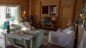 Ein gemütliches Blockhaus-Interieur mit Kamin, bequemen Sitzgelegenheiten, einem Fernseher und einem Bücherregal.