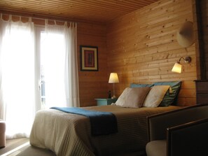 A wooden-paneled room with a bed, a nightstand, a lamp, and a picture on the wall.