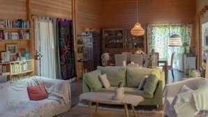 Ein gemütliches Holzhaus-Interieur mit Wohnzimmer, Essbereich und einer Bücherwand voller Bücher.