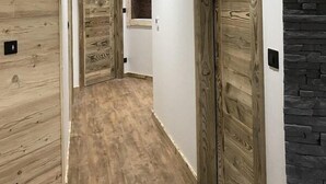 A hallway with wooden doors and a stone accent wall. - Chalet Le Lynx (Ferdrupt)