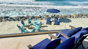 Vista de la playa con sillones de descanso y una sombrilla, con vista al océano.