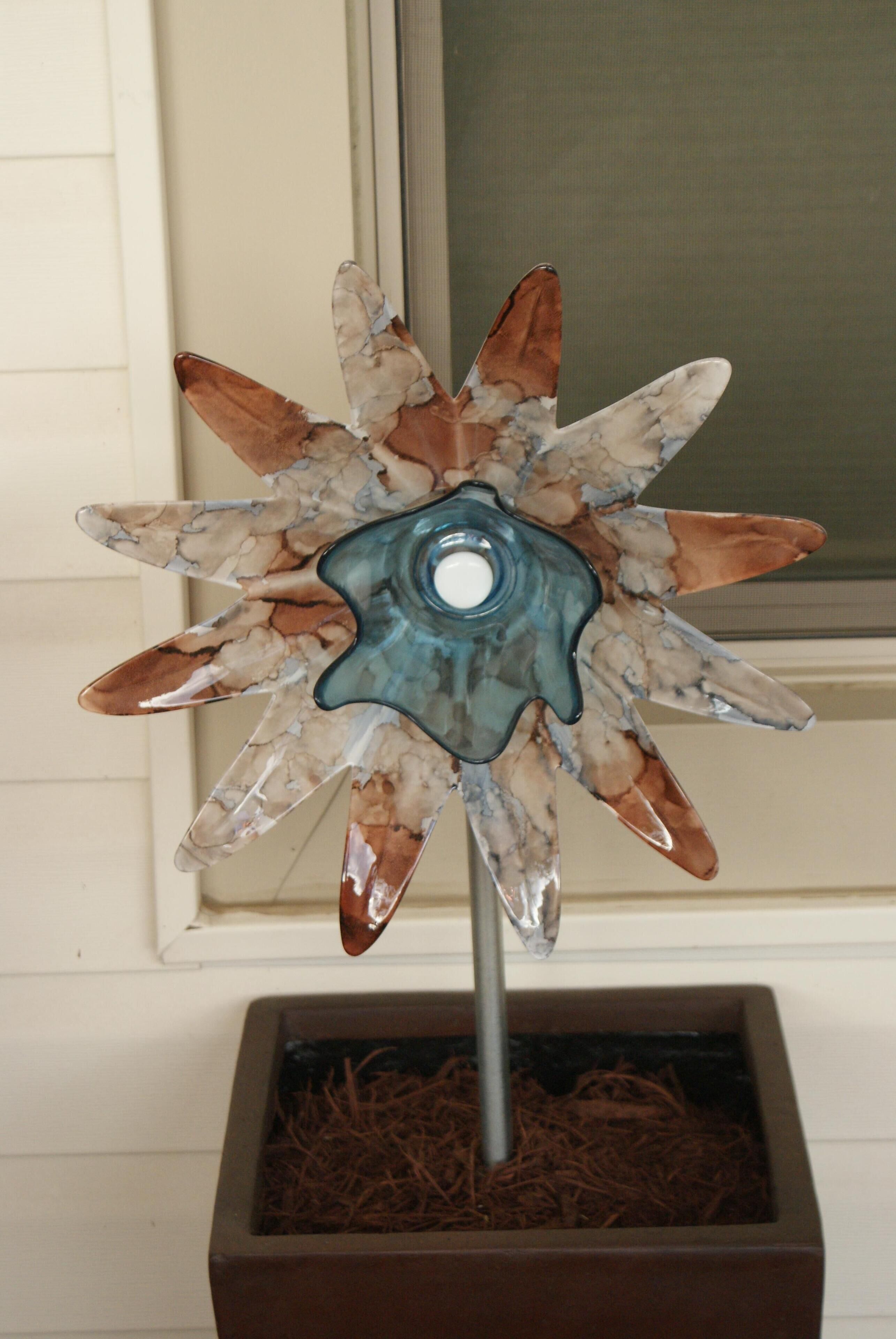 A decorative glass flower in a square planter.