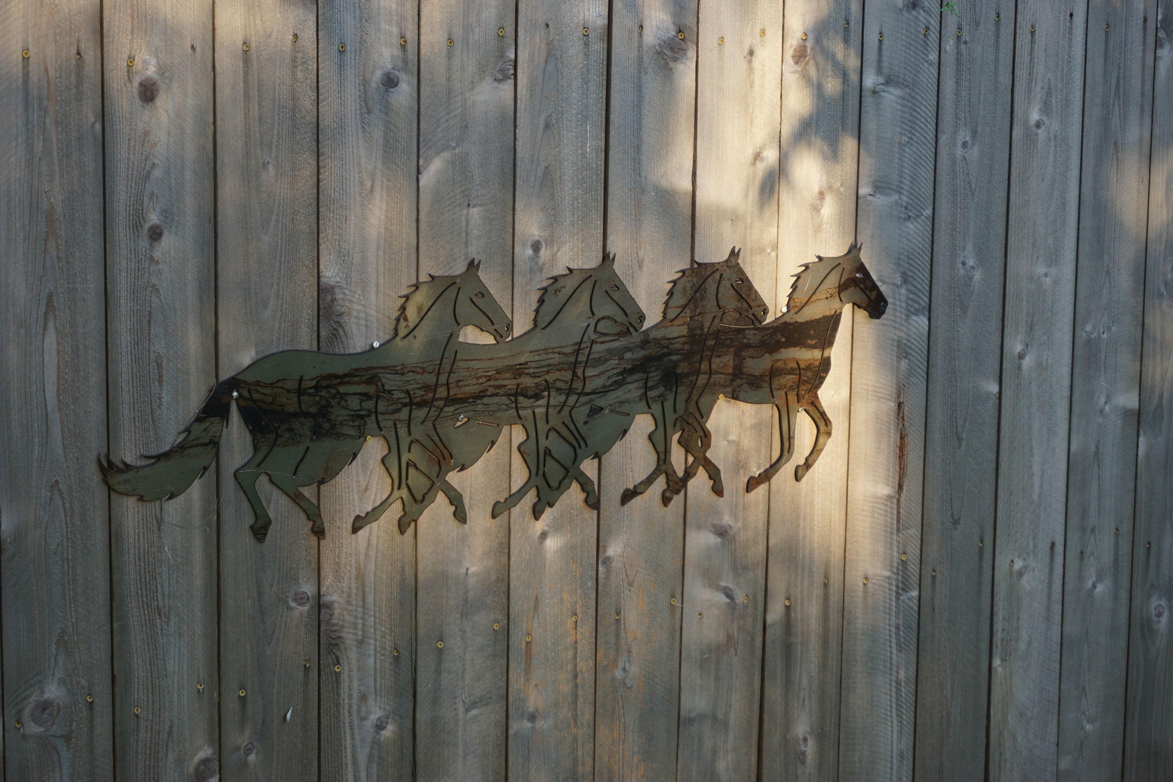 A wooden fence with a metal horse decoration.