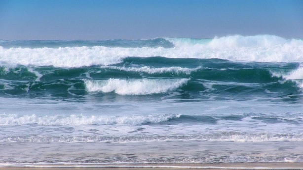 Una playa con olas rompiendo en la orilla.
