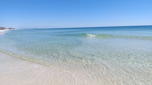 En strand med klart, lavt vand og en fjer pier.