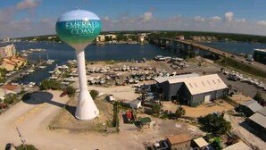 Een watertoren met de tekst 'Northwest Florida Emerald Coast', met een jachthaven en gebouwen op de achtergrond.