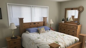 Ein Schlafzimmer mit einem hölzernen Bett, zwei Nachttischen, einer Kommode und einem Spiegel.