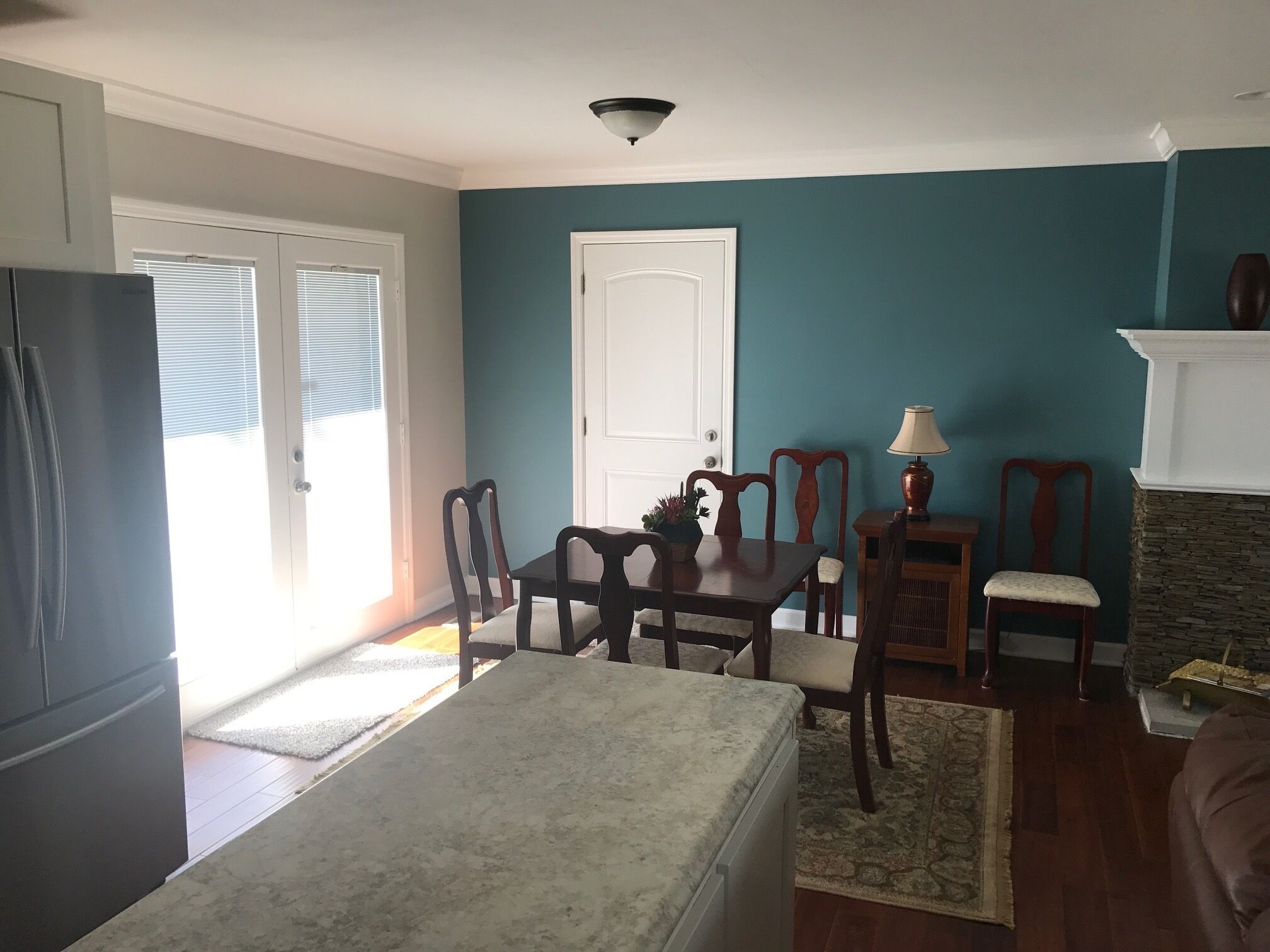 Un salon aux murs de couleur turquoise, une table à manger avec des chaises, une cheminée et un réfrigérateur.