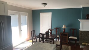 Ein Wohnzimmer mit türkisfarbenen Wänden, einem Esstisch mit Stühlen, einem Kamin und einem Kühlschrank.