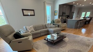 Un salon moderne avec un canapé d’angle, une table basse en verre et un tapis à motifs.