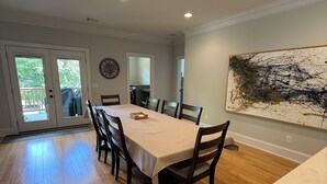 Un espace repas comprenant une table, des chaises, un comptoir de cuisine et un grand tableau abstrait accroché au mur.