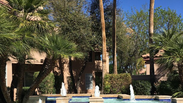 A swimming pool with a fountain, surrounded by palm trees and a building with a tiled facade. - McCormack Ranch 1st floor 2 Bed 2 Bath Condo.  Located Near Shopping, Dinning.  (Scottsdale)