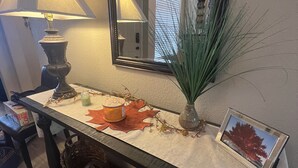 A room with a table featuring a lamp, a mirror, and decorative items including a vase with green foliage and a framed picture. - McCormack Ranch 1st floor 2 Bed 2 Bath Condo.  Located Near Shopping, Dinning.  (Scottsdale)