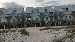 Eine Reihe von Gebäuden direkt am Strand mit Balkonen und einem sandigen Strand im Vordergrund.