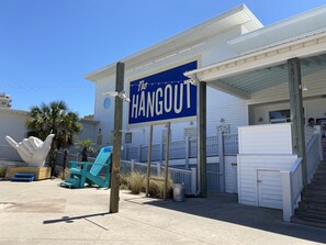 Un bâtiment sur lequel on peut lire l’inscription « The Hangout », et une zone extérieure abritée avec un escalier menant à une porte.