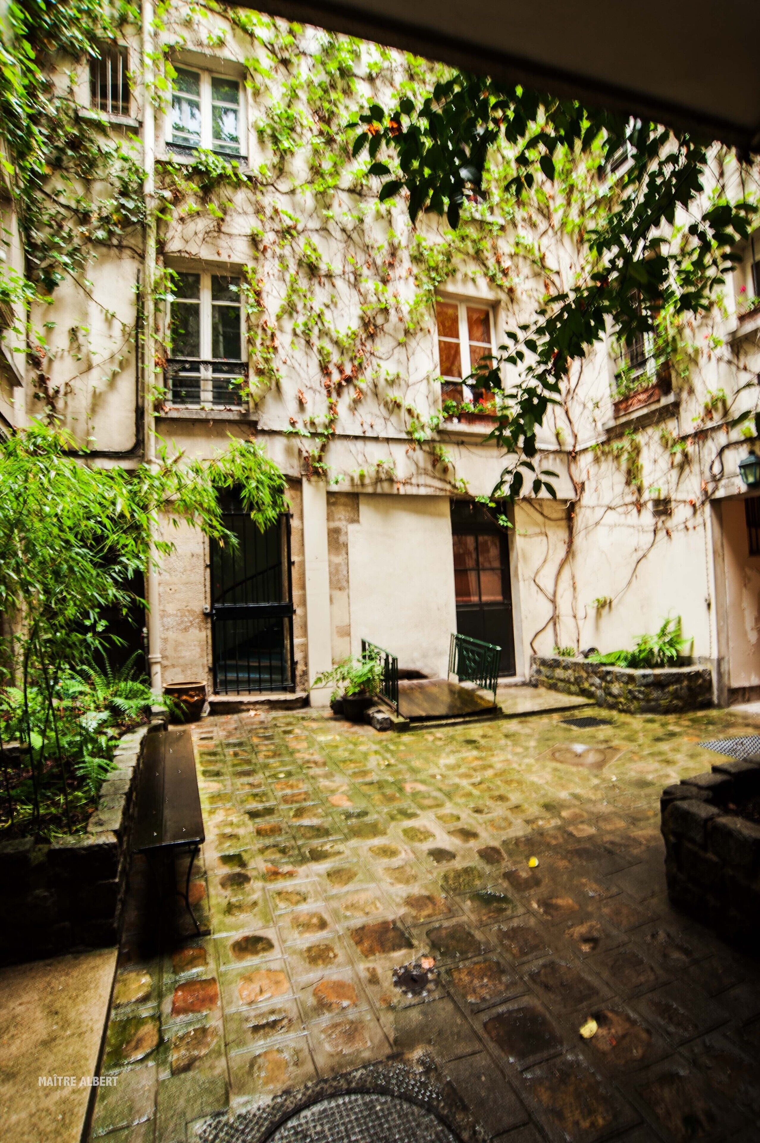 A courtyard with a tiled floor, a bench, and potted plants.