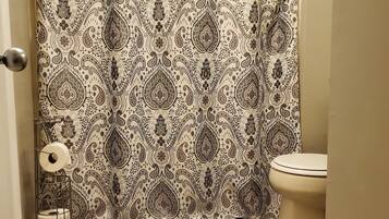 Tina con regadera, secadora de cabello, toallas, papel de baño