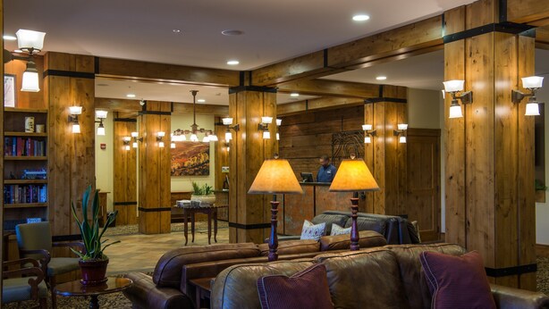A lobby with leather sofas, wooden walls, and a reception desk. - Modern Studio Condo | Fireplace and Balcony (Crested Butte)