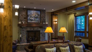 A cozy living room with leather sofas, a stone fireplace, and a painting of a mountain scene. - Modern Studio Condo | Fireplace and Balcony (Crested Butte)